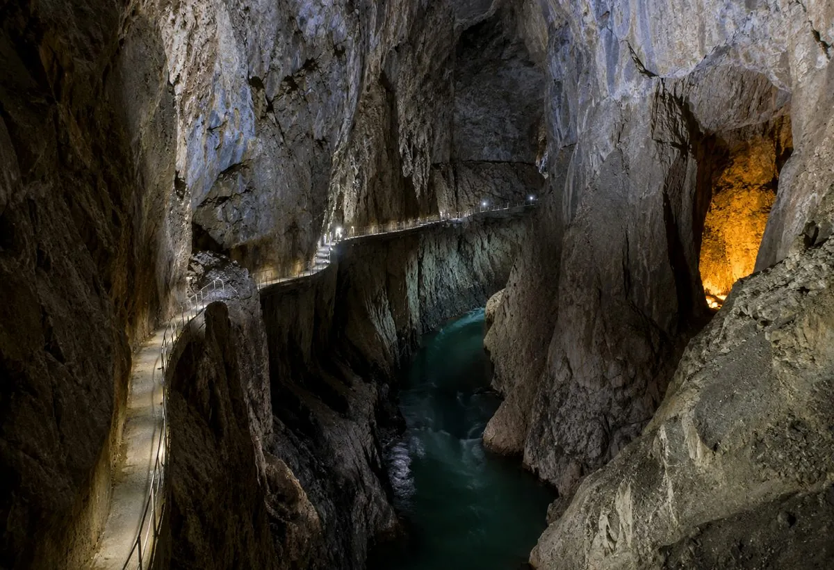 A lit walkway above an underground river inside a cave