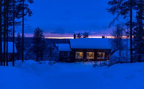 A lit log lodge in Kuusamo during the blue hour.