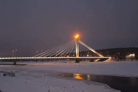 Rovaniemi at dusk, the candle bridge lit above the river.